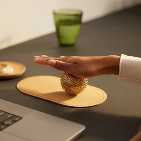 Person massiert sich am Schreibtisch die Handinnenfläche mit dem Shakti Spiky Ball