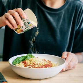 Person streut das Pasta Topping über ein Gericht